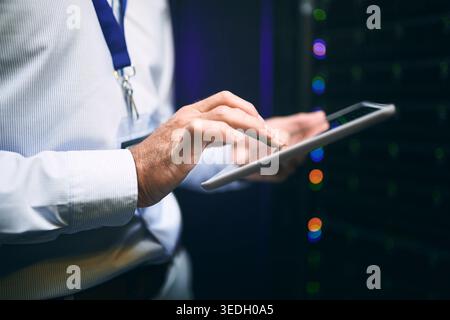 Person, hands and network with tablet in server room for cybersecurity maintenance or system backup. IT technician, engineer or working late with Stock Photo