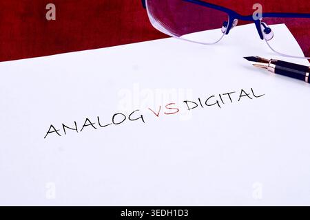 White paper displays Analog VS Digital in handwritten text. A pair of blue reading glasses and an elegant fountain pen lie nearby, set against a deep Stock Photo