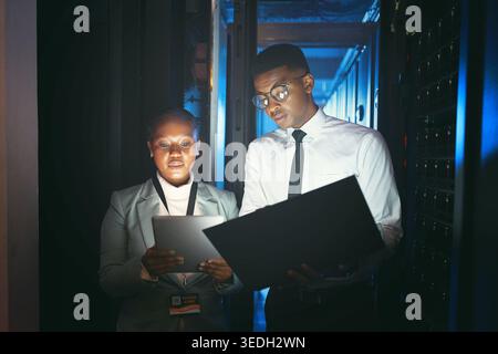 Black people, programming and tech in server room at night for research, coding and cybersecurity. Team, working late and laptop with tablet software Stock Photo