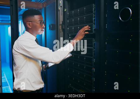 Tablet, technician or black man in server room to check database, software update or upgrade firewall. Cyber security, tech or person in data center Stock Photo