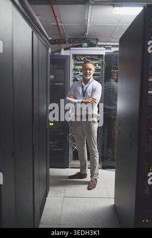 Portrait, smile or engineer in server room with arms crossed, pride or experience in system analysis. Happy, digital or mature man with confidence Stock Photo