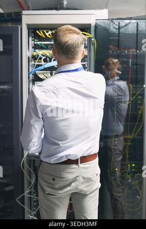 Server room, engineer and back with inspection for cybersecurity, maintenance or digital storage. Mature man, AI network or machine learning for Stock Photo