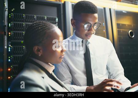Black people, reading and programming with tablet in server room for research, coding and cybersecurity. Team, review and digital for software update Stock Photo