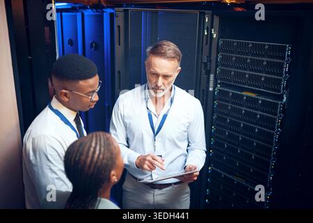 Cybersecurity, storage and tablet with team in data center together for problem solving or solution. App, collaboration and conversation with people Stock Photo