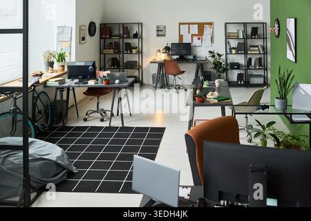 Wide angle shot of modern open plan office featuring multiple workstations, computers, and desks, presenting startup workspace concept. Ideal for business, coworking, or hybrid work marketing Stock Photo