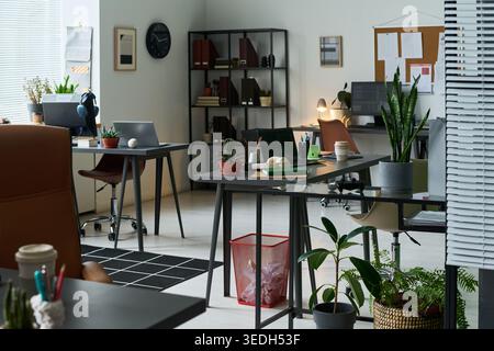 Wide shot of modern open plan office showing empty workstations with computers and desks, suggesting hybrid work setup. Suitable for workplace productivity, recruitment, or corporate communication Stock Photo
