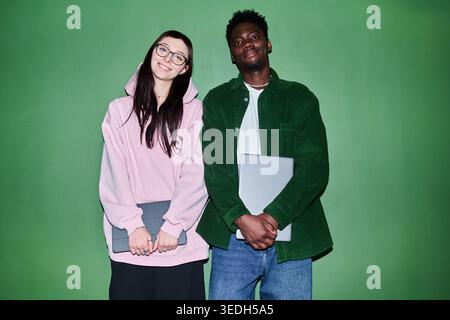 Portrait of Caucasian young woman and African American young man holding laptops and smiling at camera, representing diverse students or coworkers. For education, recruitment, teamwork marketing Stock Photo