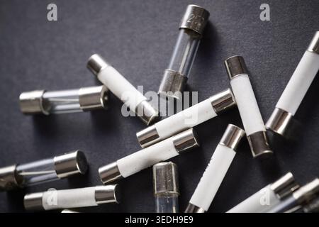 Set of miniature electrical tube fuses for overcurrent protection in electrical circuits on a black table Stock Photo