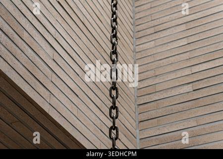 Hanging Metal Chain against a Modern Brick Wall Stock Photo