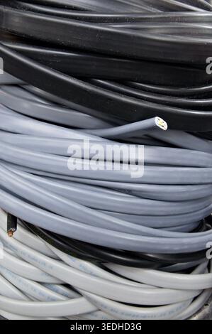 A close-up of coiled black and gray cables stacked together. Vertical Stock Photo