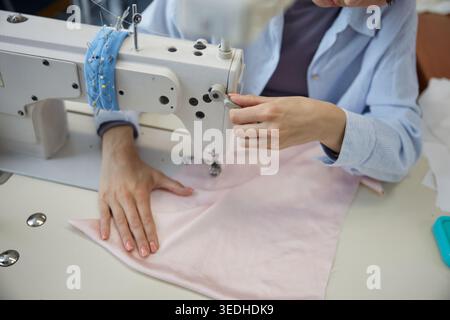 Sewing fabrics with a sewing machine in a cozy workspace Stock Photo
