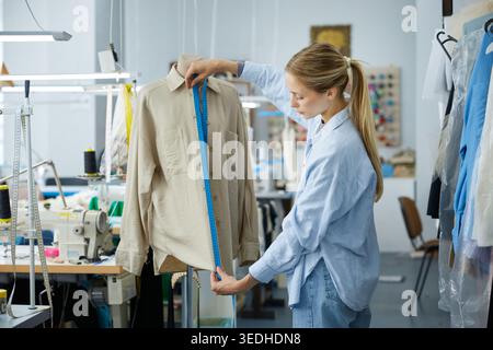 Woman clothing stylist measuring garment for precision in workshop Stock Photo