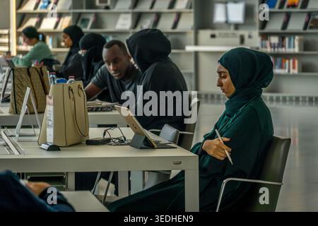 Students studying at Qatar National Library in Doha, Qatar, young Arab woman using tablet in modern public learning space. Stock Photo