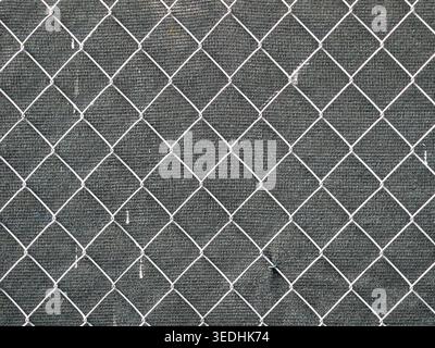 Chain link fence with diamond pattern against dark background. Front view with clear structure and geometry. Copy space. Stock Photo