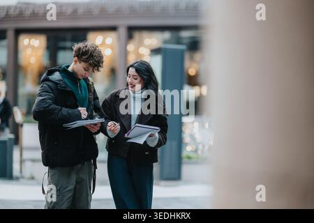 High school friends studying together outdoors with notebooks and discussing notes Stock Photo