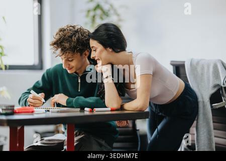 Two students studying together at a desk, smiling and collaborating on homework Stock Photo