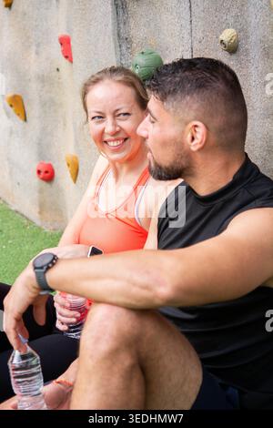 Happy mature woman and athletic man resting and talking after an outdoor climbing and fitness session. Healthy lifestyle, motivation, friendship and a Stock Photo