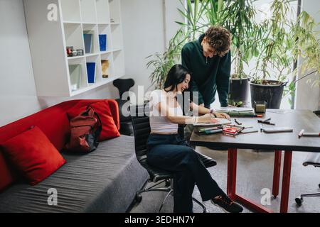 Two students collaborating and studying together at a bright modern workspace with plants Stock Photo