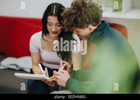 Two students studying together on a couch with notebook and markers, collaborating on notes Stock Photo