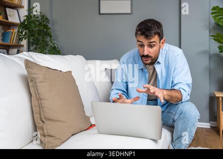 Smiling man working remotely on a laptop during a home office session, enjoying an online conversation, virtual consultation, or casual freelance proj Stock Photo