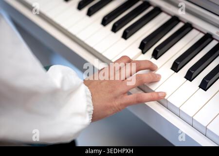 Hand Playing Piano Keyboard Close Up. Close-up of a hand pressing piano keys, showing music practice, learning, performance, and keyboard instrument Stock Photo