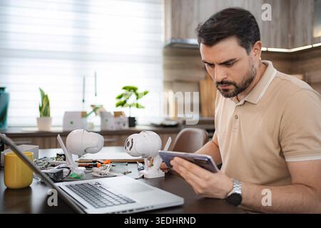 Focused technician configuring ip cameras using smartphone and laptop Stock Photo
