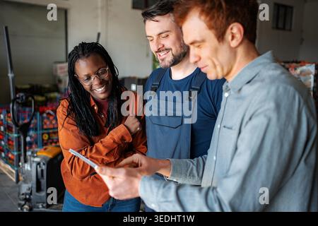 Diverse team of warehouse workers discussing logistics using a digital tablet Stock Photo