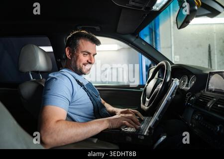 Mechanic running diagnostics on a car inside a vehicle at an auto repair shop Stock Photo