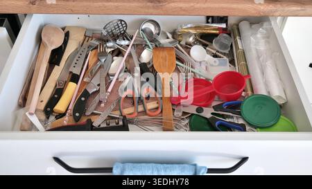 Messy Kitchen Drawer with Disorganized Cutlery Stock Photo