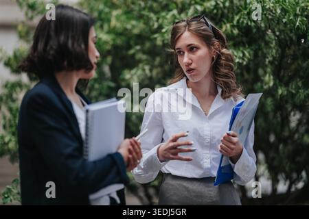 Two business colleagues discussing documents outdoors during a professional conversation Stock Photo