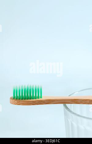 Bamboo toothbrush with green bristles resting on a glass, representing dental hygiene and eco-friendly choices Stock Photo