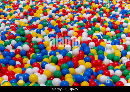 Thousands of vibrant red, blue, green, yellow, and white plastic balls creating a cheerful background Stock Photo