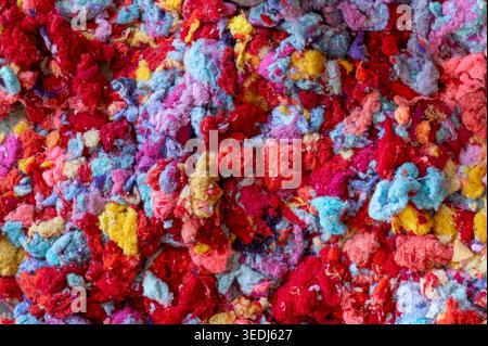 Shredded fabric scraps forming a colorful abstract background texture for textile recycling Stock Photo