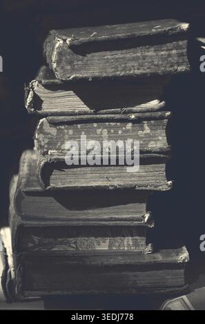 Old books for sale at flea market in Paris (France). A game of light and shadow. Selective focus. Aged dark photo. Black and white. Stock Photo