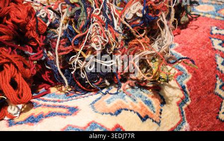 Oriental carpets and tangled wool threads in the market. "From material to product" concept. Selective focus on the threads. Stock Photo