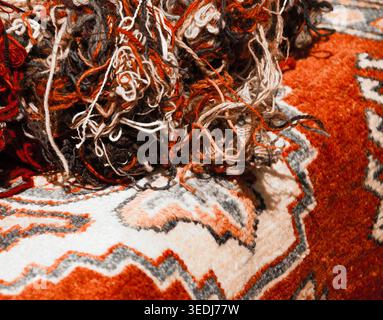 Oriental carpets and tangled wool threads in the market. "From material to product" concept. Selective focus on the threads. Aged photo. Stock Photo