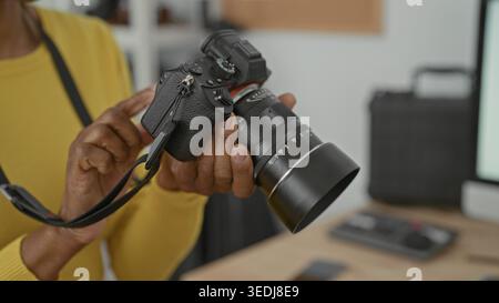 Woman adjusts camera with hands and taps dials on lens while holding strap in studio; concentration craft practice. Stock Photo