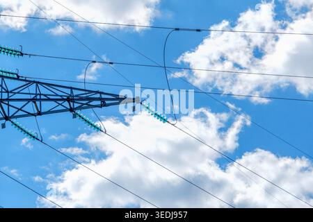 Electricity Transmission Network with Overhead Power Lines. Electrical transmission lines and insulators stretching across a bright blue sky with soft Stock Photo