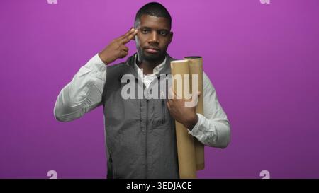 Black man holding rolled blueprints and kraft tubes, wearing grey vest and white shirt, points finger to temple in studio with purple backdrop; planni Stock Photo