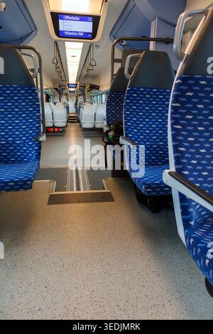 Uffenheim, Germany. March 31th, 2026. Aisle view of a Deutsche Bahn regional train with rows of empty blue seats and overhead display screens. Stock Photo