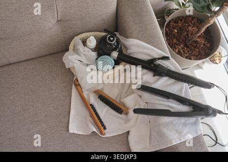 Hair styling tools, brushes, and bath products on a towel, ready for beauty and self-care Stock Photo