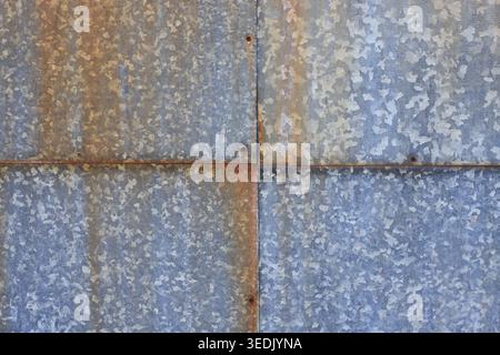 Galvanized steel sheets with rust spots and aged rivets. Industrial background and metallic texture with signs of corrosion. Vintage architectural bac Stock Photo
