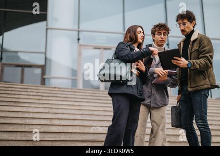 High school students collaborating with a tablet on campus steps during a casual study session Stock Photo