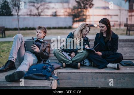 High school students studying and chatting together on a park bench at dusk Stock Photo