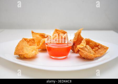 fried wonton with chili sauce dipping served in a white plate on white table Stock Photo