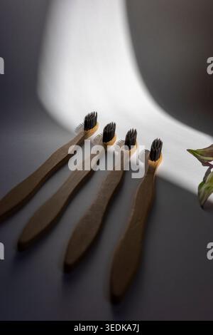 Four bamboo toothbrushes on white background in dramatic sunlight, minimal eco bathroom setup. Concept: zero waste hygiene Stock Photo