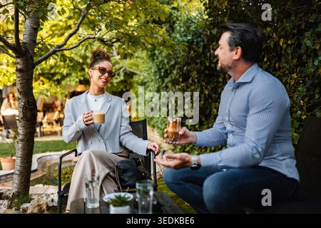 Couple enjoying coffee together at an outdoor garden cafe Stock Photo