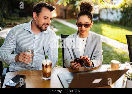 Business colleagues collaborating outdoors using mobile technology Stock Photo