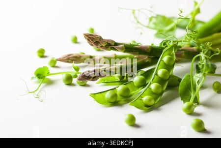 Fresh green  peas pods  with  sprouts and green asparagus on white wooden background. Concept of healthy eating, fresh green vegetables. Stock Photo