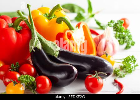 Various types of fresh vegetables and herbs on a  white wooden background. Concept of healthy eating, fresh vegetables. Stock Photo